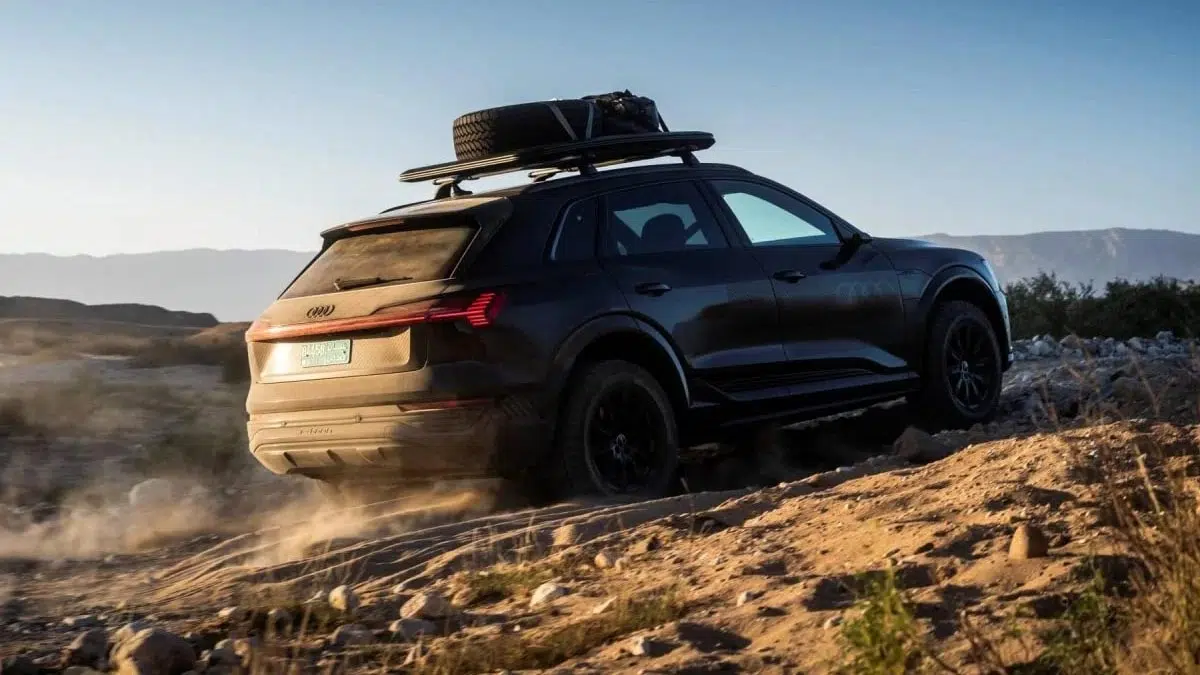 Vue arrière de l’Audi Q6 e-tron tout-terrain, montrant ses feux LED et sa galerie de toit, sur un sentier rocailleux.