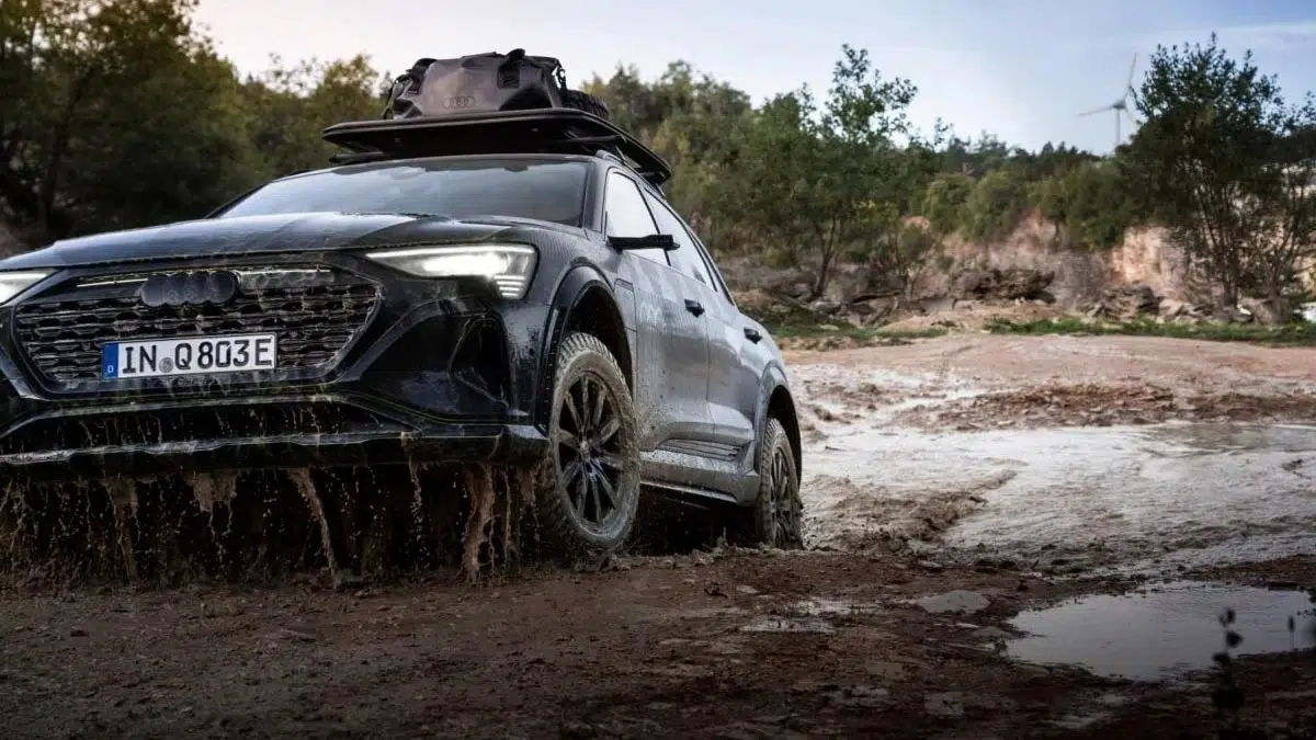 Vue latérale de l’Audi Q6 e-tron tout-terrain sur un terrain difficile, avec ses pneus tout-terrain et son design élargi.