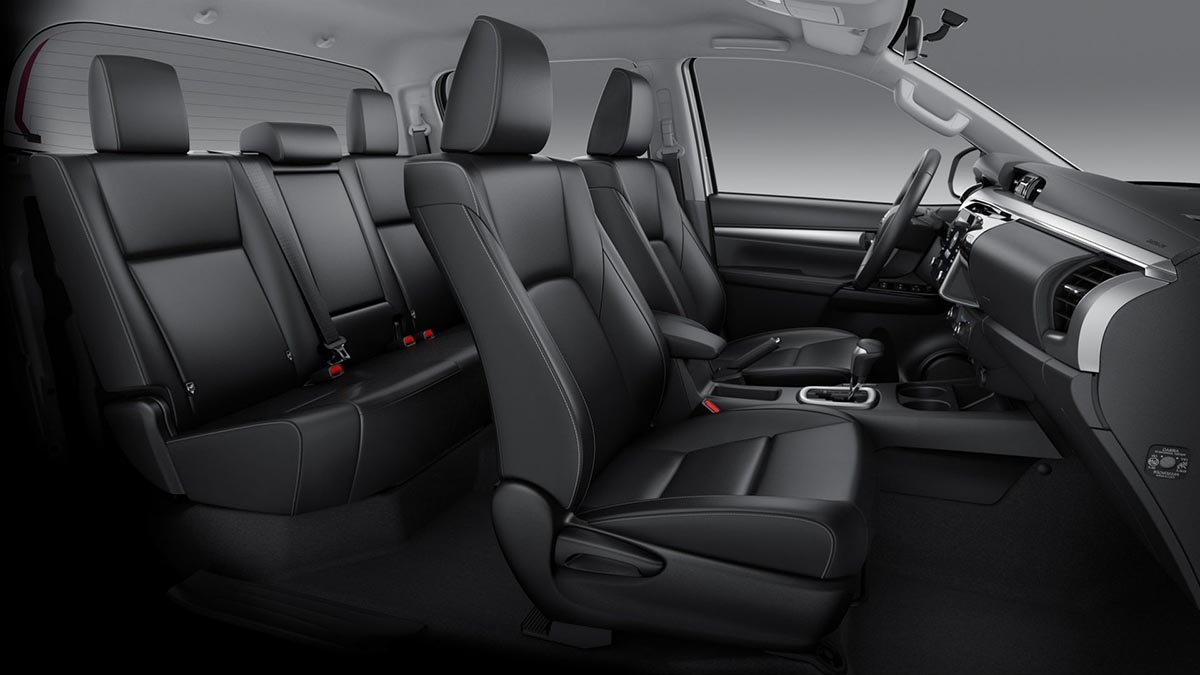 Vue des sièges avant et de la banquette arrière du Hilux, montrant l'espace intérieur et les finitions.