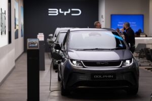 Véhicules BYD exposés devant un graphique montrant le dépassement financier de Tesla