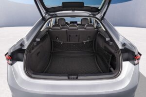 Berline familiale spacieuse équipée du moteur 1.5 eTSI avec coffre ouvert révélant son immense capacité de 640 litres, stationnée à côté d'une BMW Série 5 pour comparaison de taille.
