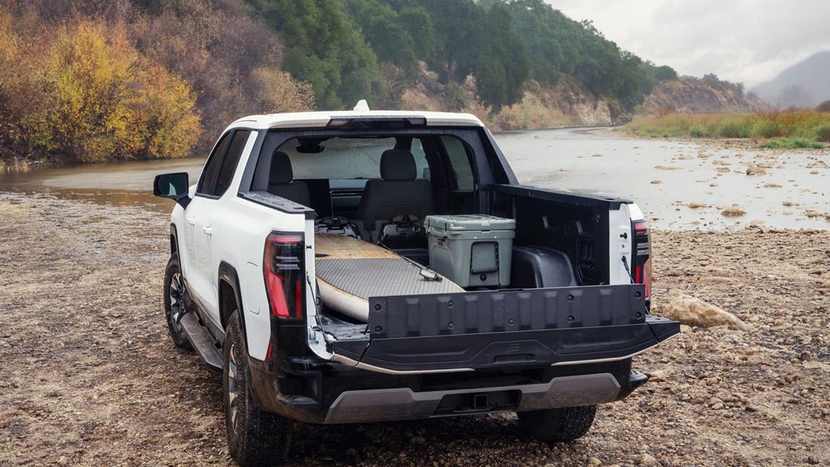 GMC Sierra EV AT4 2026 vu de l’arrière avec hayon MultiPro ouvert et coffre eTrunk