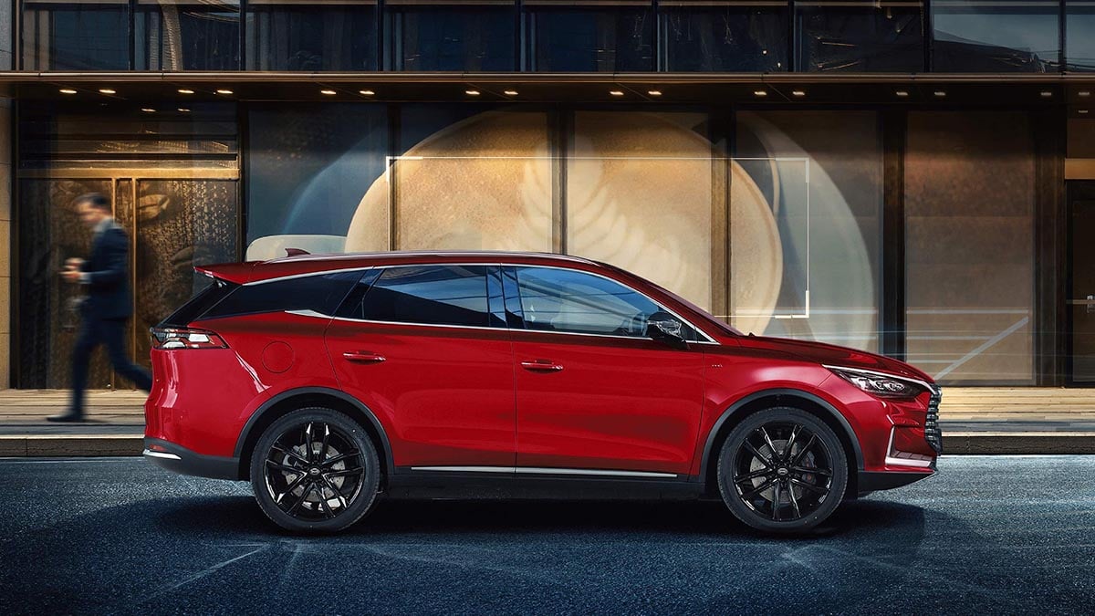 Vue latérale du BYD Tang blanc 7 places électrique garé sur route, design élancé et jantes noires 20 pouces
